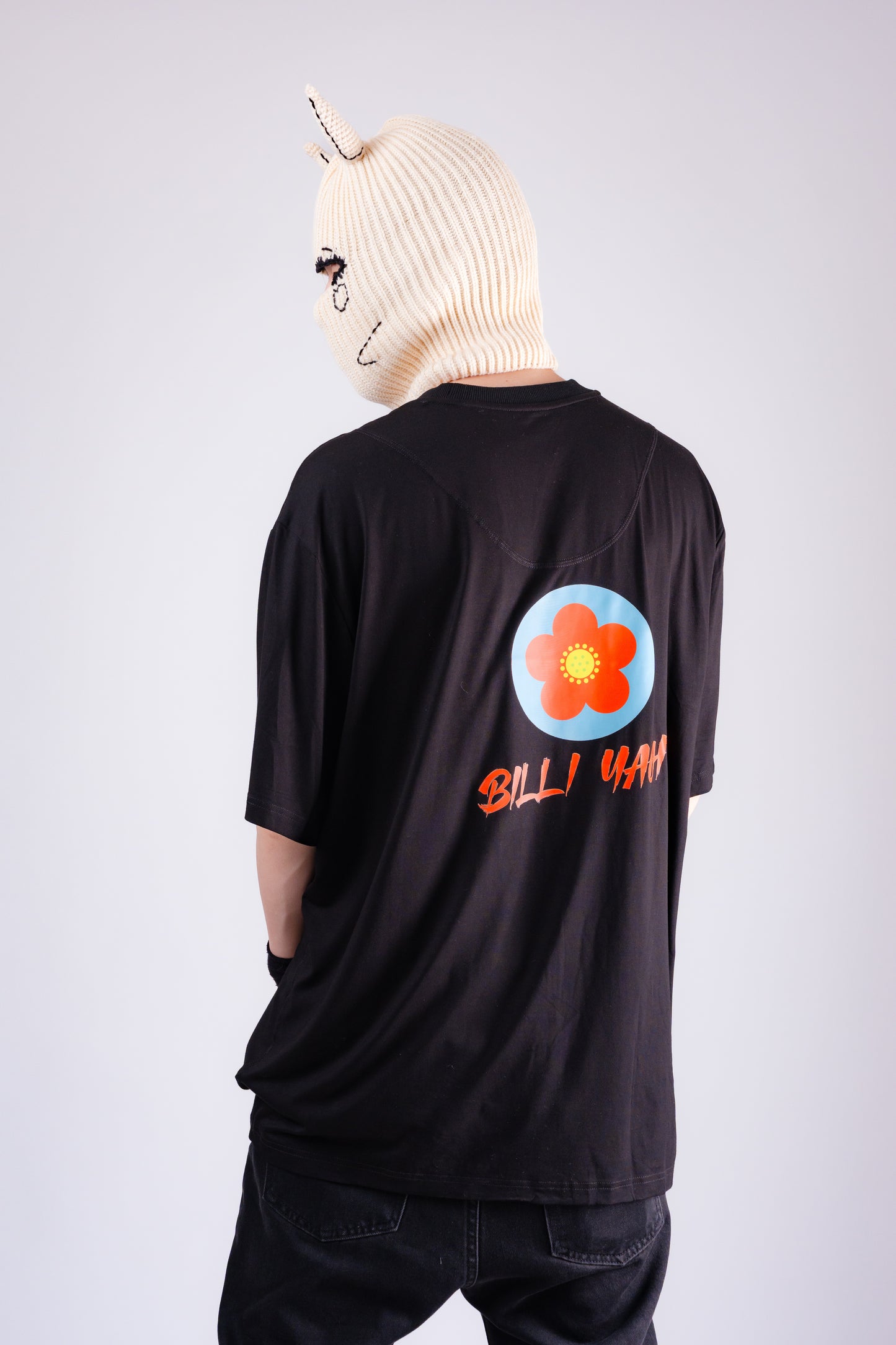 Person wearing a black t-shirt with a colorful design and text, standing against a plain background.