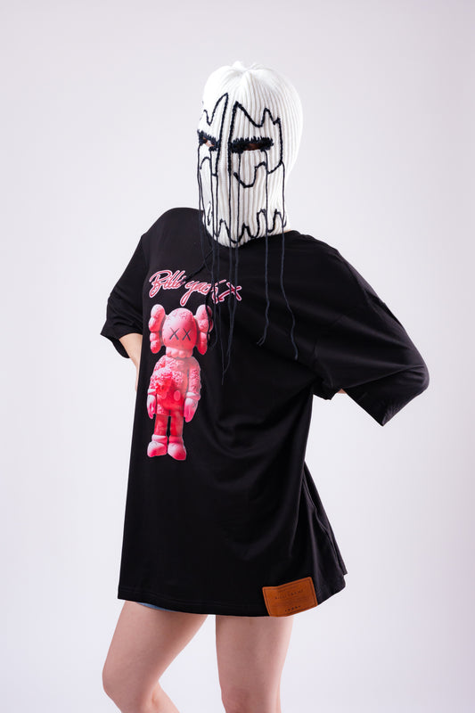 Person wearing a black hoodie with a pink cartoon character on the back, standing against a white background.