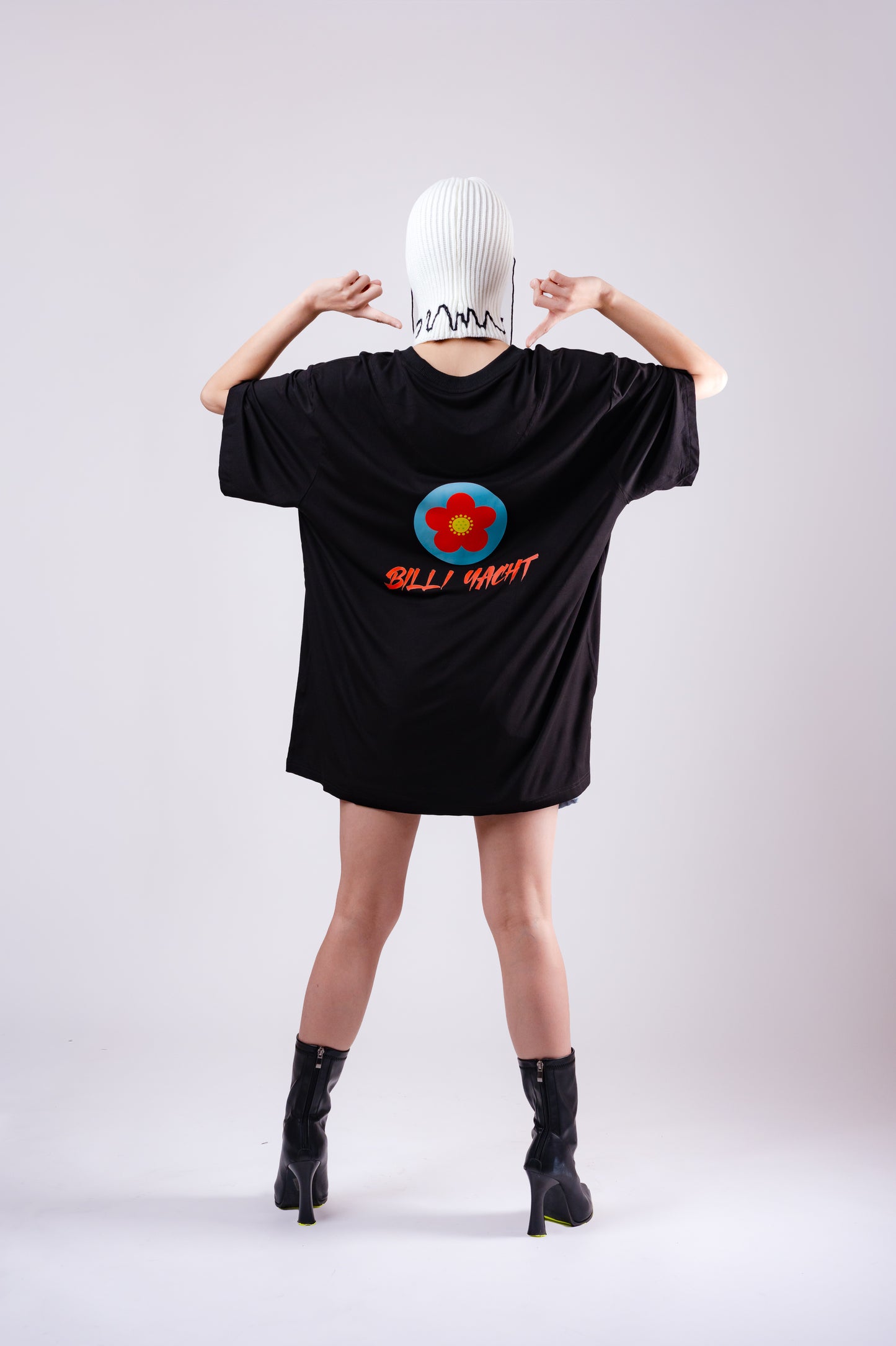 Person wearing a black oversized t-shirt with a colorful design and text on the back, standing against a plain background.