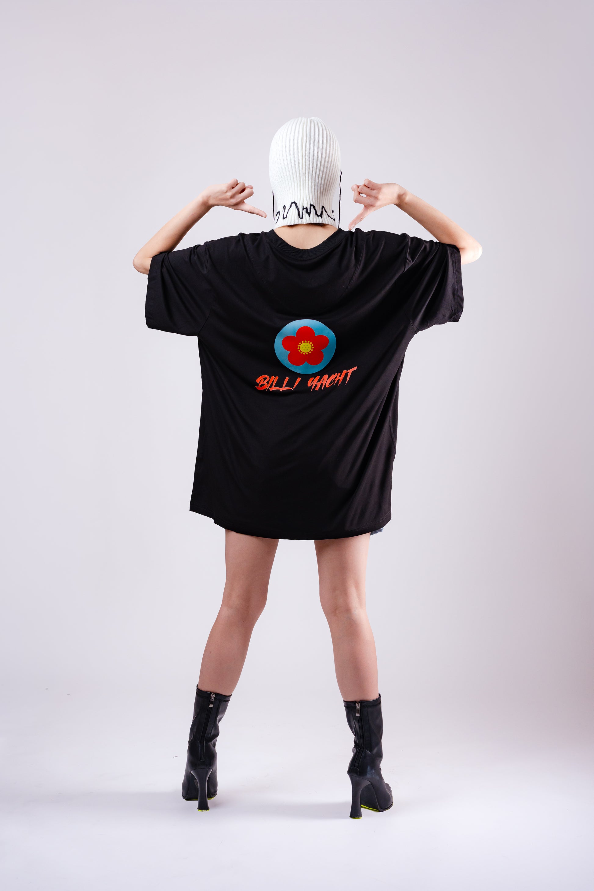 Person wearing a black oversized t-shirt with a colorful design and text on the back, standing against a plain background.