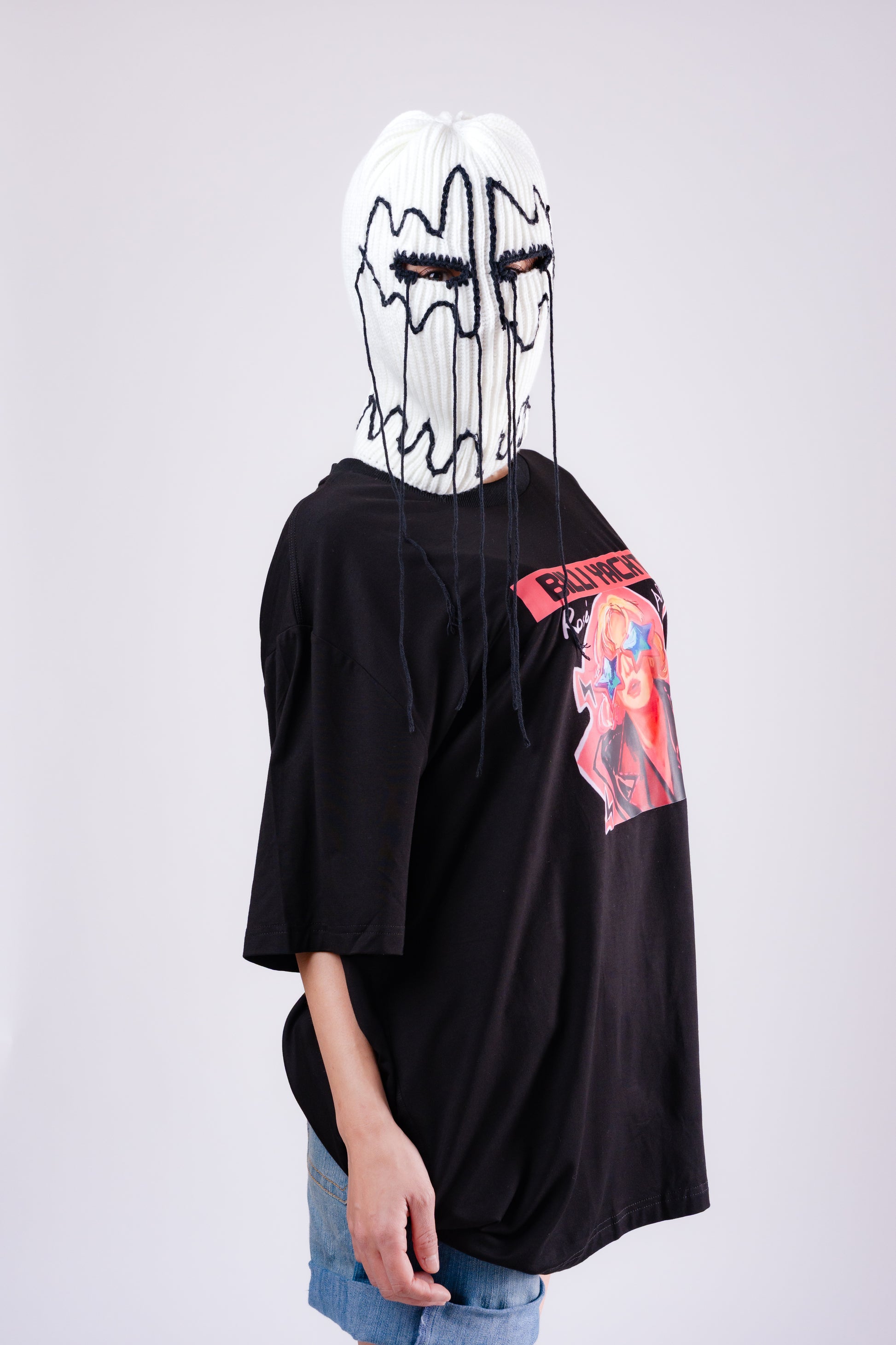 Person wearing a black oversized t-shirt with colorful graphics on a plain background