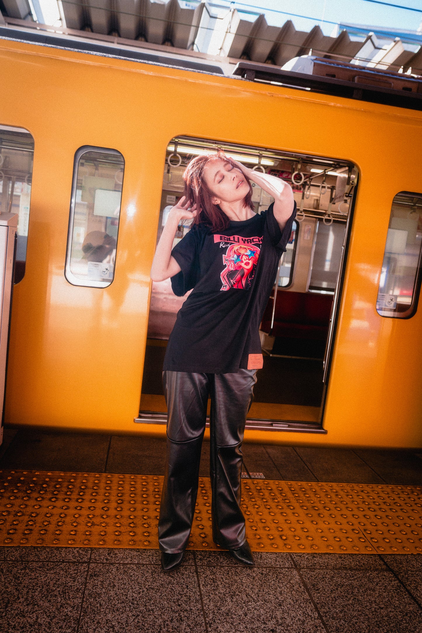 Person standing on a train platform with a large poster of a person on the train wall.