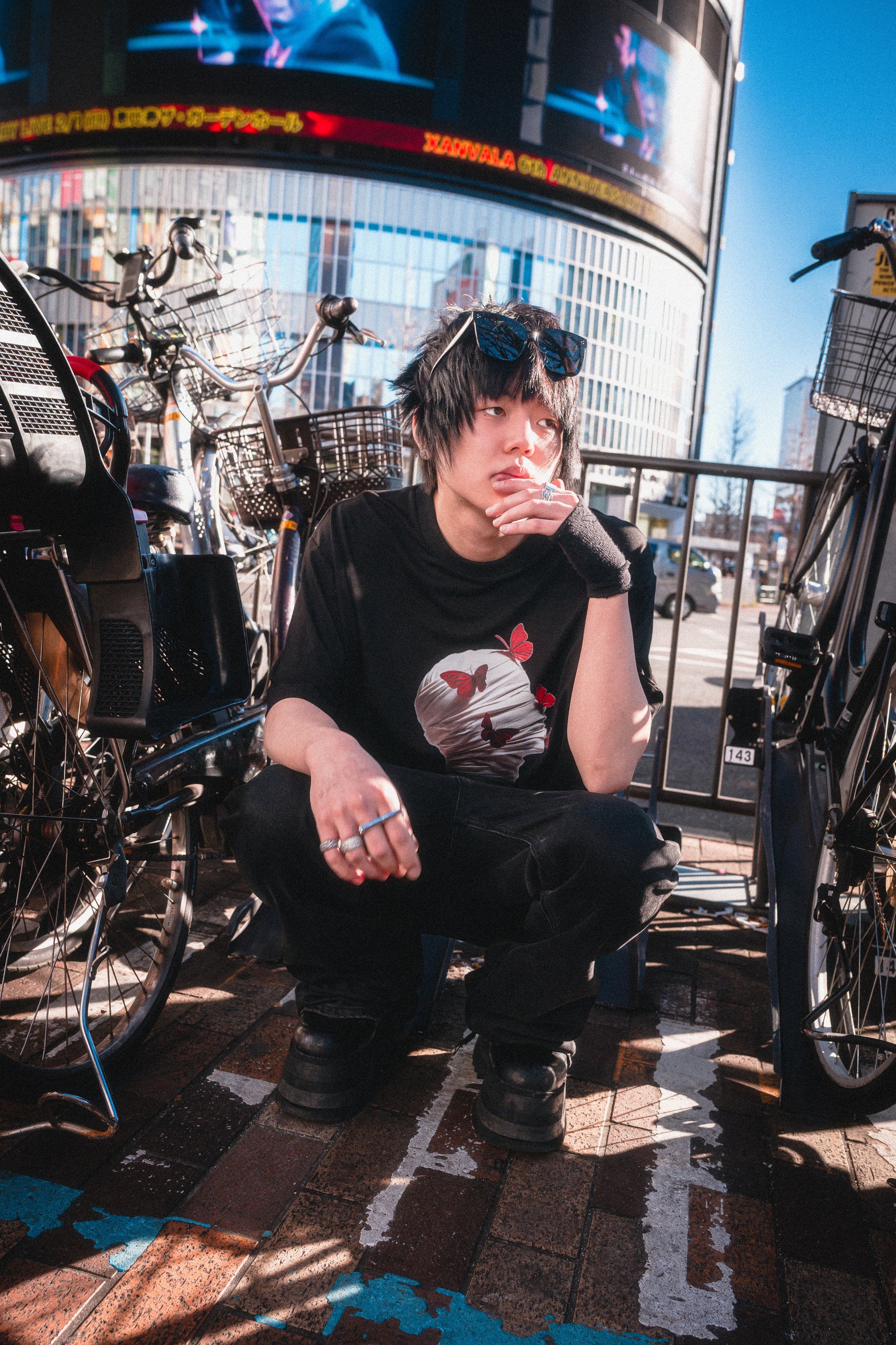 Person sitting on a street with a cityscape and billboards in the background