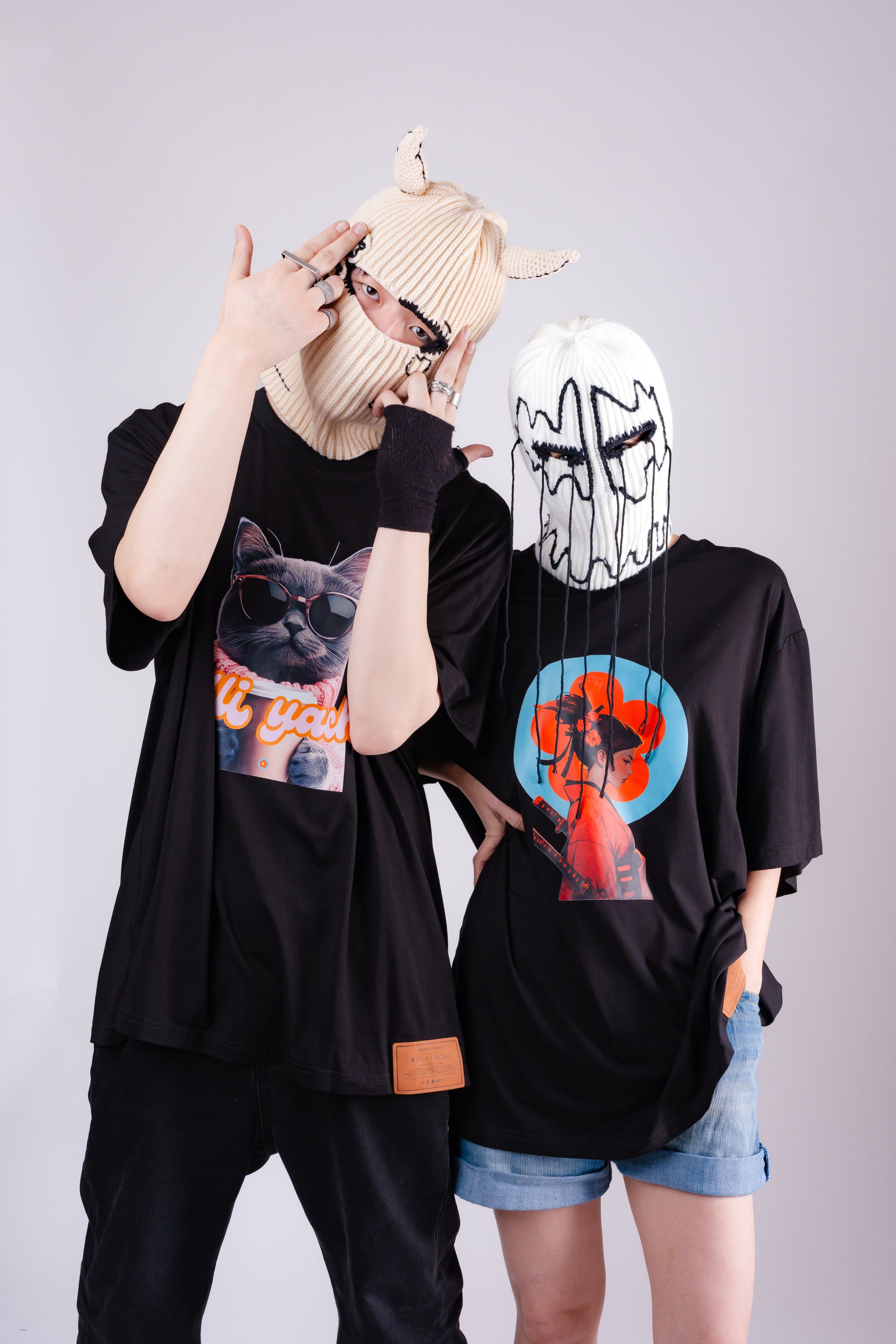 Two people wearing black t-shirts with graphic designs on a plain background