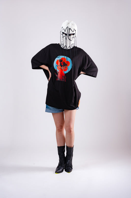 Person wearing a black oversized t-shirt with a colorful graphic on the back, standing against a white background.
