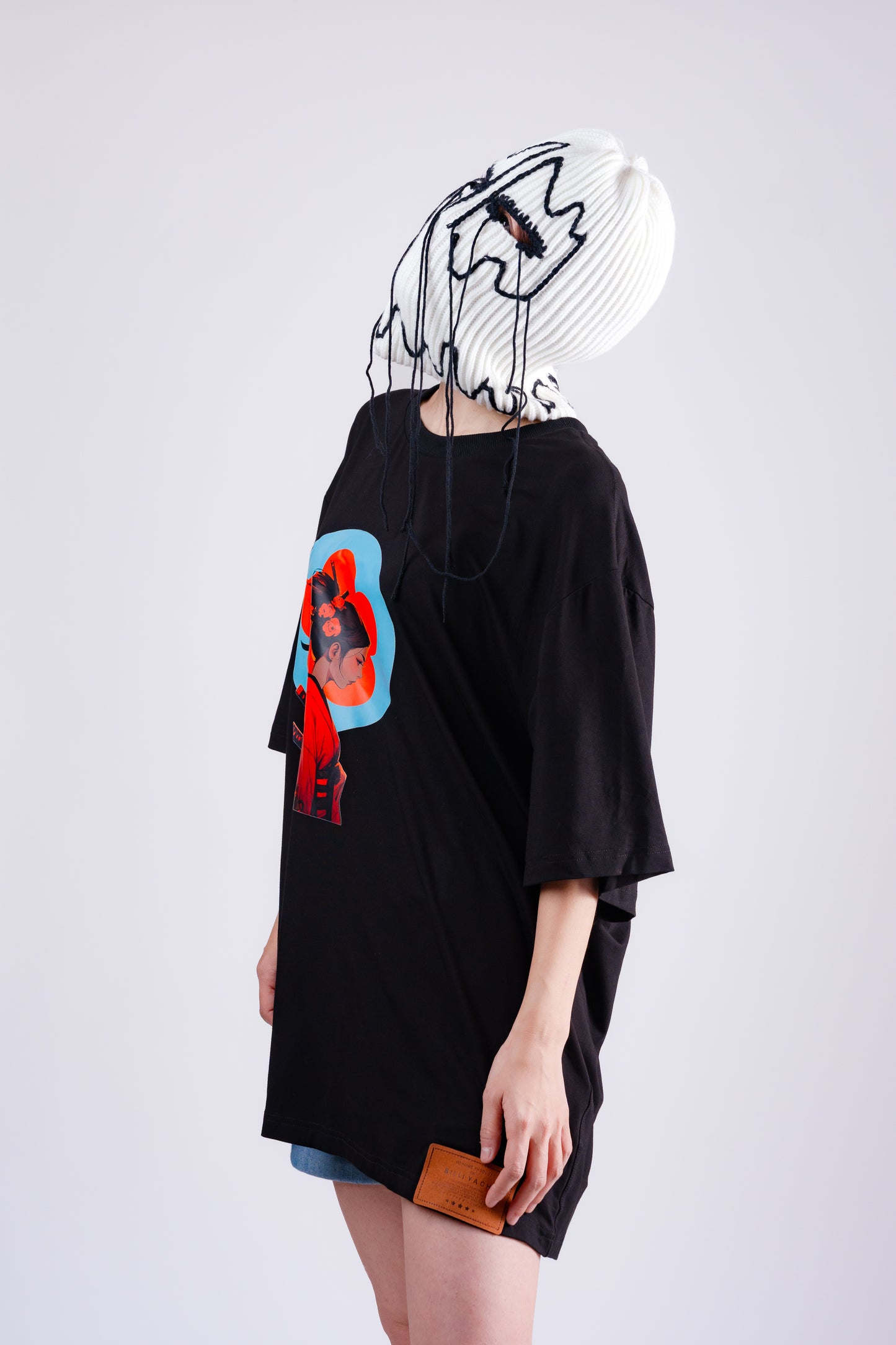 Person wearing a black oversized t-shirt with a colorful graphic design on a white background
