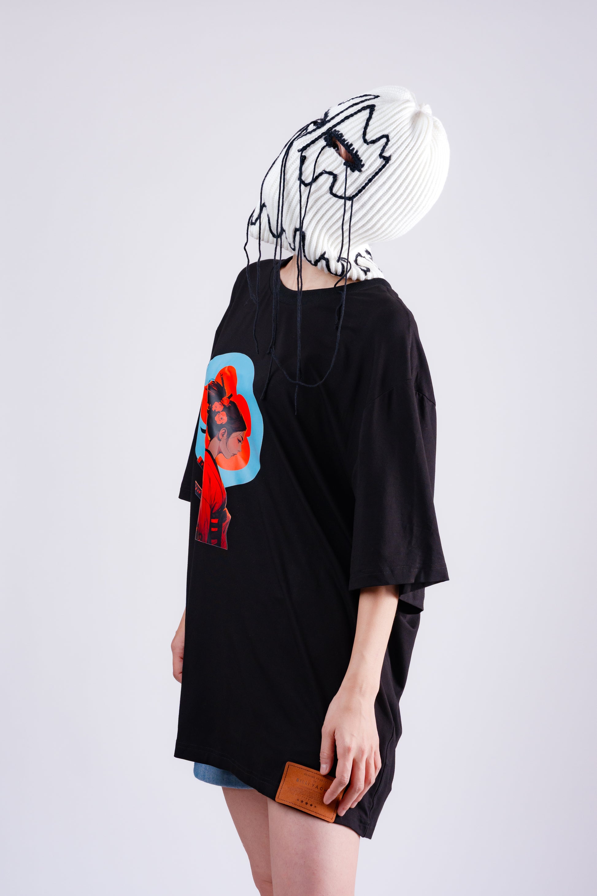 Person wearing a black oversized t-shirt with a colorful graphic design on a white background